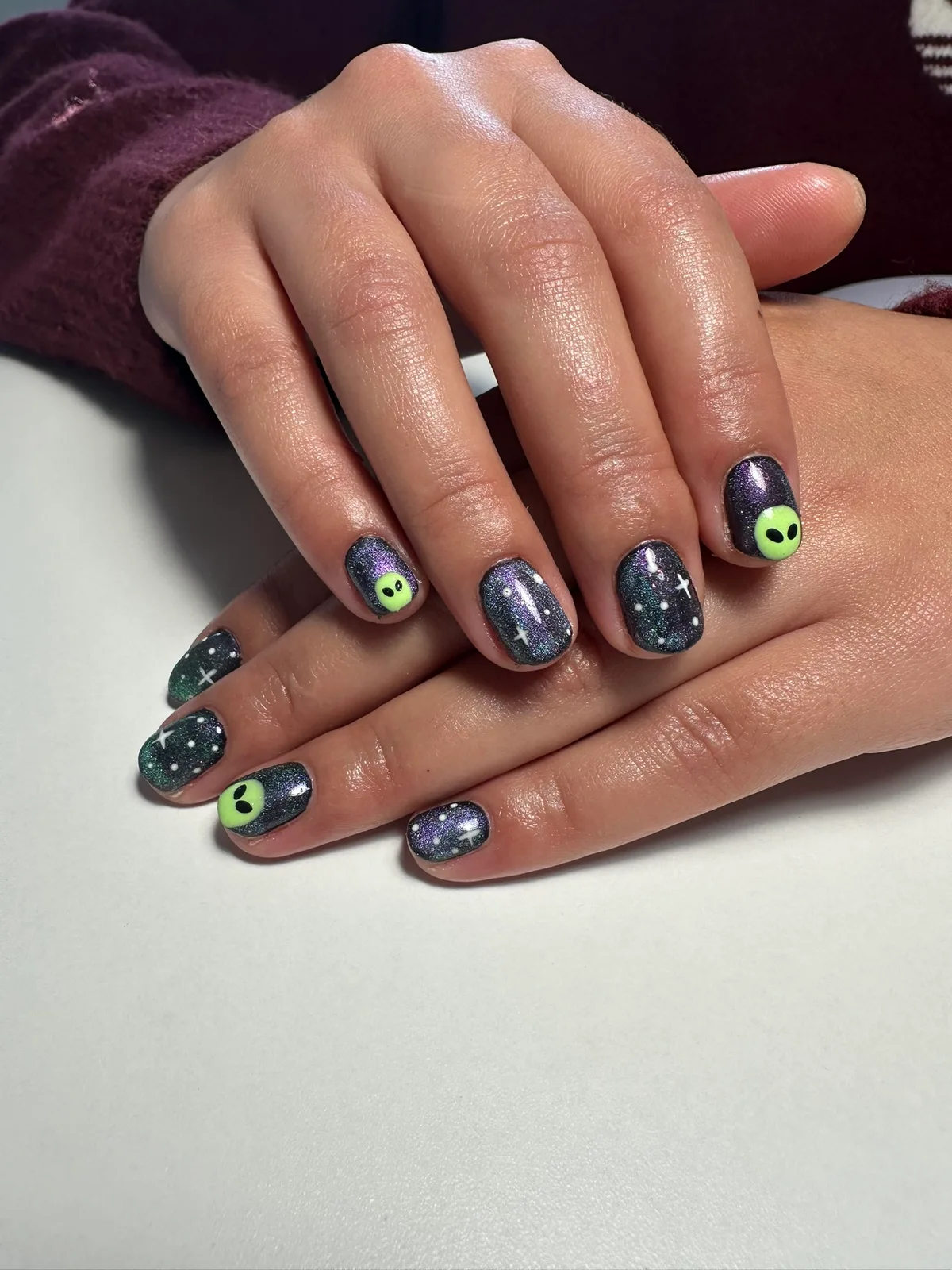 Nail art com desenhos coloridos sobre uma base escura